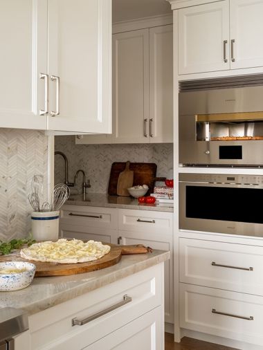 &ldquo;Pizza Night&rdquo; celebrations await in the kitchen, that is lined with a herringbone Walker Zanger, Tangent Hive mosaic Calacatta backsplash from United Tile, with returns in Calacatta Classico. Schaub Menlo Park Collection hardware dresses the cabinets.