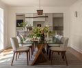 Linking with living room lighting, a Rima sconce embellishes custom wainscoting, and the Cerno Vix Linear wood pendant ties perfectly to the kitchen&rsquo;s Camur Linear fixture.