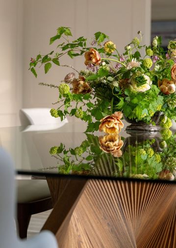 The dining room, with direct sight line to the kitchen, adds another point of connection in the home. Elements like the handcrafted Orbit walnut base overlaid with a glass top from Natisa and dining chairs with walnut legs reiterate the look of natural wood.