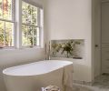 To round out the primary bathroom, the formerly oversized tub was replaced with a Hibiscus Oval Acrylic Freestanding Tub from Signature Hardware, and paired with a Kohler Purist Bath Filler in polished nickel from Ferguson Home. Pella Windows bring in soft natural light.