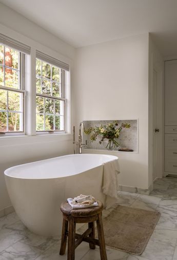 To round out the primary bathroom, the formerly oversized tub was replaced with a Hibiscus Oval Acrylic Freestanding Tub from Signature Hardware, and paired with a Kohler Purist Bath Filler in polished nickel from Ferguson Home. Pella Windows bring in soft natural light.