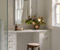A custom vanity by Creative Woodworking, Inc. is topped with Marble Calacatta Caldia from Stratus Surfaces. The metal frame mirror in polished nickel was sourced from Rejuvenation. The floor is covered in Marble Calacatta Classico from Walker Zanger.