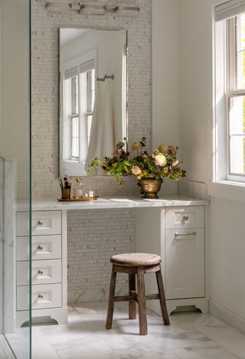 A custom vanity by Creative Woodworking, Inc. is topped with Marble Calacatta Caldia from Stratus Surfaces. The metal frame mirror in polished nickel was sourced from Rejuvenation. The floor is covered in Marble Calacatta Classico from Walker Zanger.