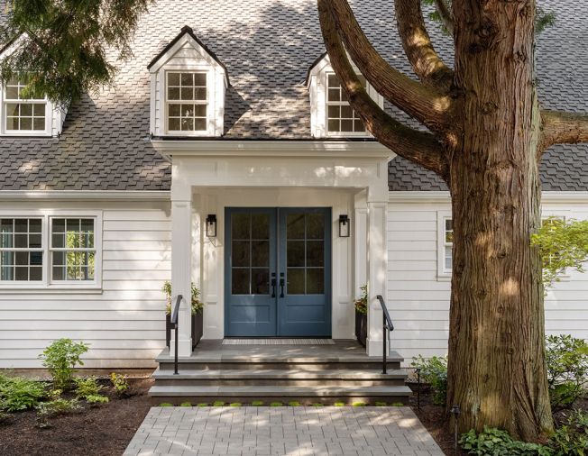 The reconfigured entry door, now painted in Sherwin Williams &ldquo;Smoky Blue,&rdquo; was pushed out to match the line of the exterior. The house is dressed in Benjamin Moore &ldquo;Simply White,&rdquo; and the roofing refinished with Presidential Shake TL by CertainTeed. A new walkway of Marenakos Stone pavers lead the way.