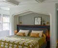 The primary bedroom is all custom and now includes a walk-through closet, custom bed frame, headboard and shelving, and ceiling beams added overhead. Linens are from Schoolhouse, headboard upholstery from Trio.