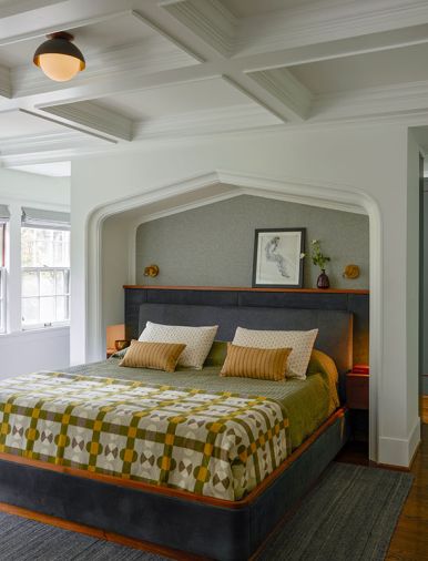 The primary bedroom is all custom and now includes a walk-through closet, custom bed frame, headboard and shelving, and ceiling beams added overhead. Linens are from Schoolhouse, headboard upholstery from Trio.