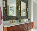 The custom walnut vanity with honed marble counter is designed by Bright Designlab with lacquer and finishing by Master Furniture Makers. The wall sconces were sourced from In Common With, brass mirrors from Rejuvenation, and Purist plumbing fixtures from Kohler.