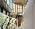 The two-story entry features a sweeping staircase with a Skywall railing system and cedar risers that echo the cedar ceiling. On the right, doors lead to a closet, powder room and bedrooms.