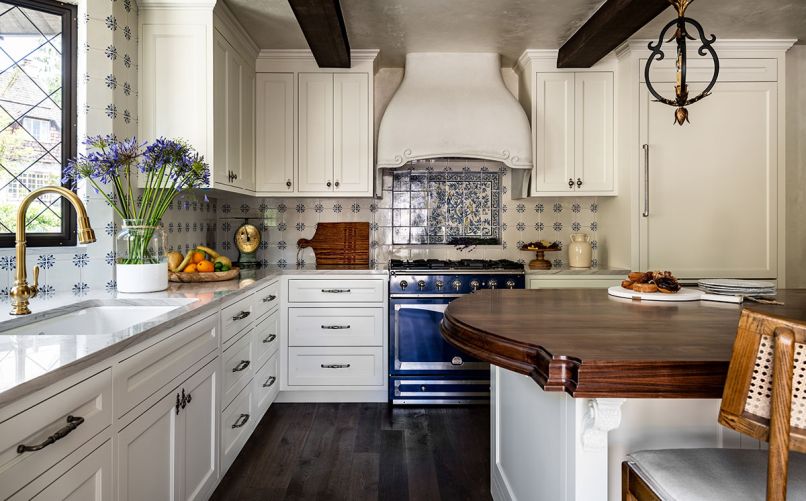 The ceramic tile backsplash in the kitchen is from Solar Antique Tiles, including the Portuguese Full Mural Reproduction behind the stove, tying in the La Cornue range. The perimeter counters are polished quartzite from Arizona Tile, while the island has custom walnut butcher block. The Artifacts faucet and Riverby sink are both from Kohler.