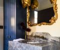 The storage closet cabinetry is painted the same blue as the tub, while Edith Pendants from Arteriors hang before the mirror.