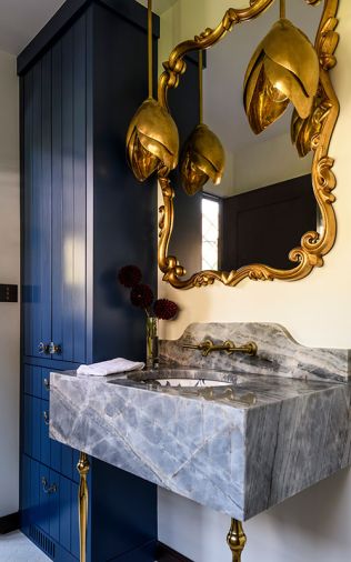 The storage closet cabinetry is painted the same blue as the tub, while Edith Pendants from Arteriors hang before the mirror.
