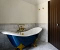 In the primary bathroom, the freestanding tub was painted &ldquo;Washington Blue&rdquo; from Benjamin Moore and has a Waterworks bath filler in aged brass from Rejuvenation.