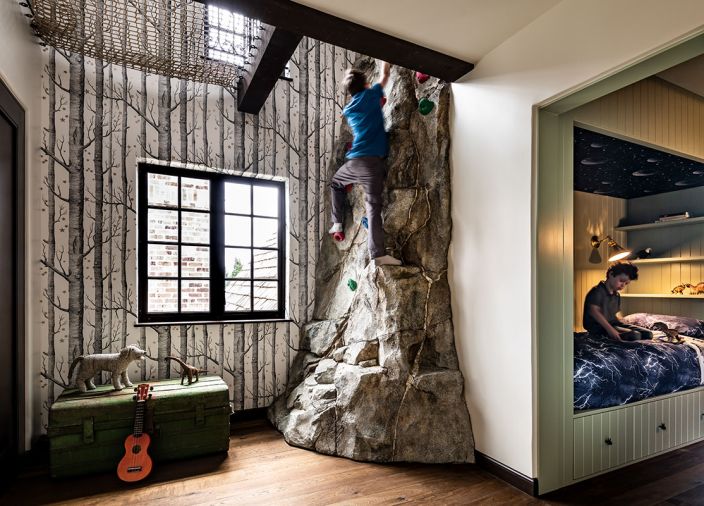 The children have a custom climbing &ldquo;rock&rdquo; wall fabricated by Turnstone Construction. The wallpaper is the &ldquo;Woods & Stars&rdquo; pattern from Cole & Son, while in the bunk room, there&rsquo;s Blue Planetarium wallcovering from Superfresco.