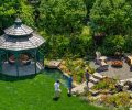 In the backyard, a stream runs to the ten-foot octagon wood gazebo from Amish Country Gazebos. The foot bridges over the stream were custom-painted to look like stone. In the fire pit area, the firebowl with optional tabletop is from Paloform.