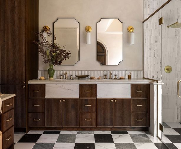 The vanity was fabricated with custom cabinets, an elegant neutral countertop, and Brizo Invari faucets from Ferguson Home. The tri-color marble floor nods to the home&rsquo;s existing checked floors in the entry.