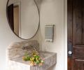 Homeowner Alicia Jones redid the powder room with consultation from Allison Lind Interiors. For it, Jones chose a McGee and Co. mirror to hang over the fluted stone sink, found on Etsy.