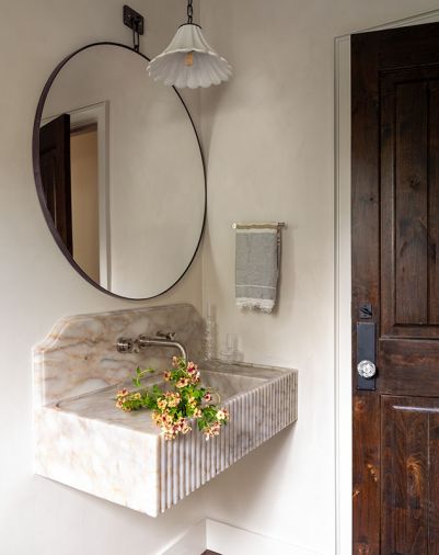 Homeowner Alicia Jones redid the powder room with consultation from Allison Lind Interiors. For it, Jones chose a McGee and Co. mirror to hang over the fluted stone sink, found on Etsy.