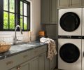The homeowner took the lead on the laundry room design with custom cabinetry, cabinet hardware from Top Knobs, a Saratoga quartzite counter, and a Brizo faucet. The backsplash consists of a dimensional fluted tile. Two stacked washer-and-dryer units maximize efficiency, making this hardworking space as functional as it is stylish.