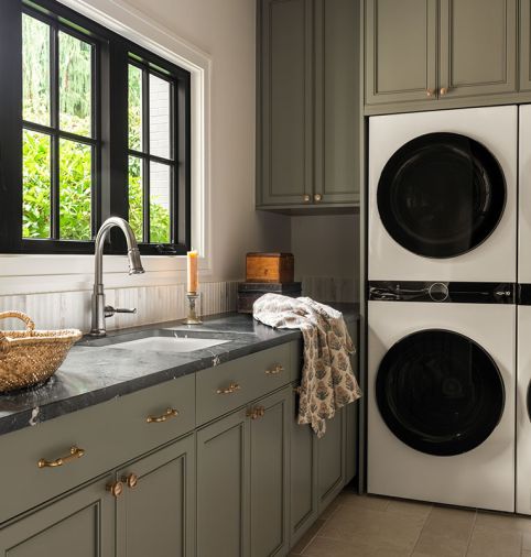 The homeowner took the lead on the laundry room design with custom cabinetry, cabinet hardware from Top Knobs, a Saratoga quartzite counter, and a Brizo faucet. The backsplash consists of a dimensional fluted tile. Two stacked washer-and-dryer units maximize efficiency, making this hardworking space as functional as it is stylish.