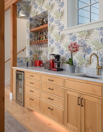 The beverage center, supported by alder cabinetry and Carrara marble counters, includes Everitt&rsquo;s favorite luxuries; a beverage fridge, coffee station, instant hot water, and playful wallcovering from Ballard Designs.