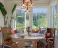 The sunroom, which looks out into the back garden, has a custom jute rug on the ceiling for sound dampening, a Turkish pendant light, antique chairs, and a stone table from Anthropologie.