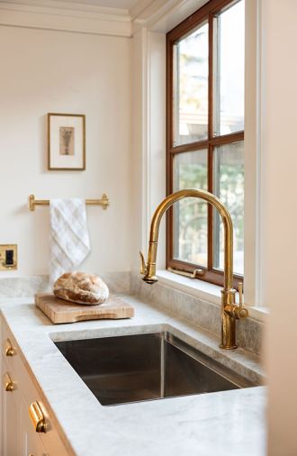 In the kitchen, an unlacquered brass Segovia faucet and Taj Mahal quartzite from Bedrosians Tile & Stone infuse patina and nuance.