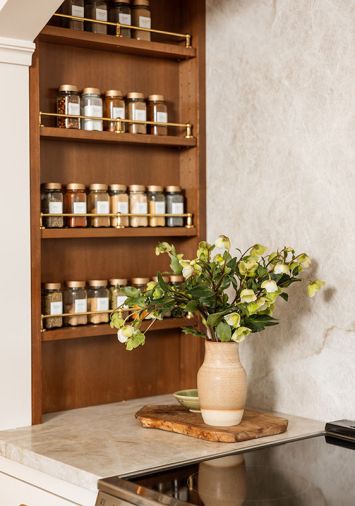 While an existing cabinet concealing the HVAC couldn&rsquo;t be moved, spice storage was cleverly crafted to flank the range with unlacquered brass gallery rails from Rejuvenation.