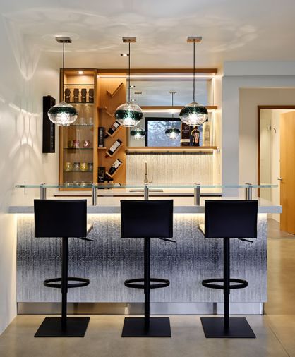For the bar, the homeowner chose quartz counters from Bedrosians Tile & Stone, and mosaic tile from Artistic Tile for the backsplash and island front. The custom cabinetry is by Contour Woodworks.