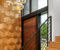 In the foyer, the custom wood wall was designed by Ranjini Rajan and made by Contour Woodworks, with porcelain floor tile from Architectural Surfaces. The blown glass pendants are by artist Julie Conway from Iluminata Art Glass Design.