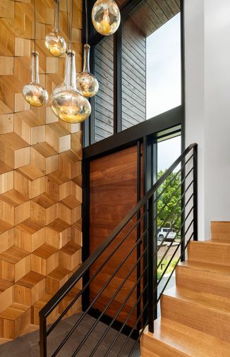 In the foyer, the custom wood wall was designed by Ranjini Rajan and made by Contour Woodworks, with porcelain floor tile from Architectural Surfaces. The blown glass pendants are by artist Julie Conway from Iluminata Art Glass Design.