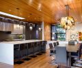 The kitchen has custom-tailored, sustainable Italian cabinets from Pedini NW in a Moka finish, with Misterio Gold quartz counters from Architectural Surfaces. The dining room includes a salvaged local walnut tree table from Urban Hardwood with a blown glass chandelier made by artist Julie Conway.