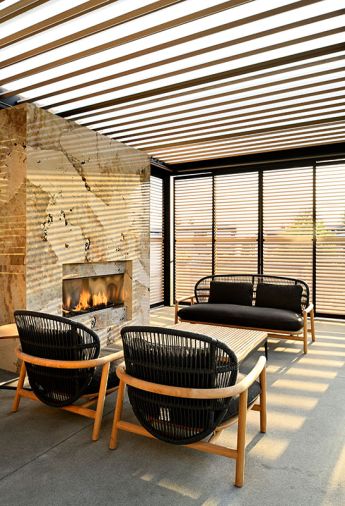 Under the pergola by Renson, there&rsquo;s an outdoor fireplace covered in Dekton cladding from Cosentino, as well as chairs, loveseat and table from Summer House. The pergola has a motorized louvered roof.
