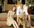 Craig Hartzman, daughter Emmarose, and Golden-doodle Samson on their sunny front porch.