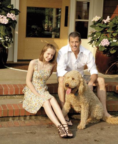 Craig Hartzman, daughter Emmarose, and Golden-doodle Samson on their sunny front porch.