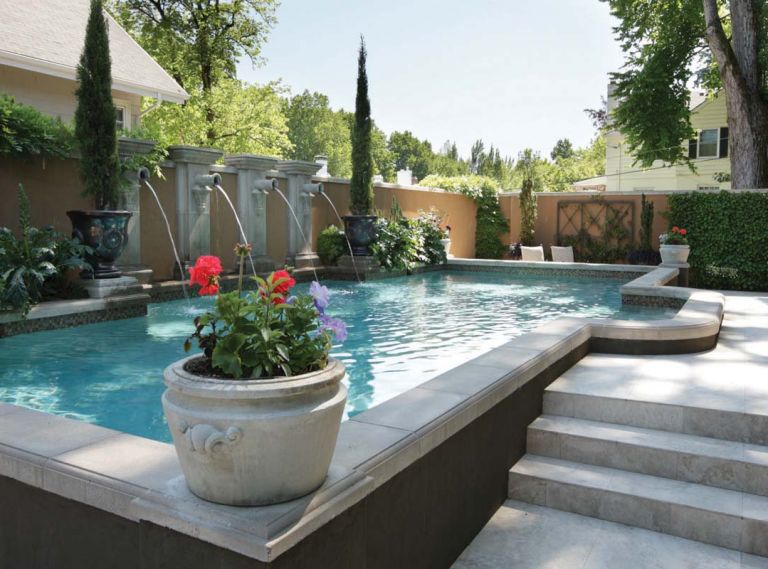 Dark espresso colored stucco outlines the raised 14’x 36’ pool that spans the Brennekes back yard. Putting together the pre-cast pool pieces to create squared off corners took great mathematical precision, says landscape architect Craig Kiest. Lisa plants the colorful seasonal flowers for the pool’s corner pots, as well as the heirloom roses in the bed at left, grown from seed in St. Paul, Oregon.