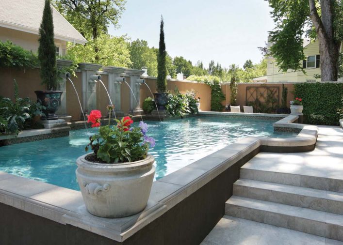 Dark espresso colored stucco outlines the raised 14’x 36’ pool that spans the Brennekes back yard. Putting together the pre-cast pool pieces to create squared off corners took great mathematical precision, says landscape architect Craig Kiest. Lisa plants the colorful seasonal flowers for the pool’s corner pots, as well as the heirloom roses in the bed at left, grown from seed in St. Paul, Oregon.