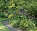 Susan Bates has wisely outlined the perennial borders with a wide fringe of gravel, so that she and her guests can give flowering plants a close inspection. Easy access to plants makes their maintenance easier. The gravel also saves wear and tear on the lawn, and keeps mowers from nicking precious plants. The packed gravel provides firm, non-muddy footing.