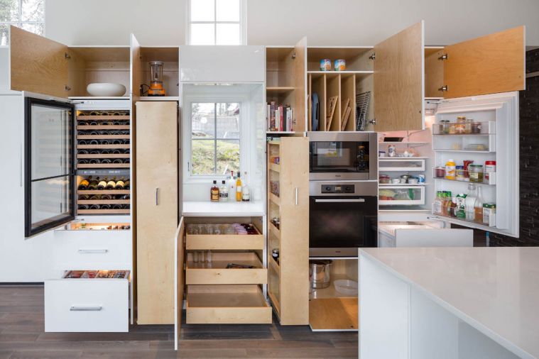 High on the homeowners’ must-have list was copious amount of storage. To fulfill that request, Vanillawood built a center island and installed custom cabinetry on three sides of the kitchen-and-dining area. On the long wall of the space, the cabinetry allows a window to peek through and incorporates a wine refrigerator, microwave, oven and refrigerator/ freezer. Cabinet doors open to reveal drawers, cubbyholes, vertical storage and pullout shelving. Self-closing drawers beneath the cooktop counter and island provide readily accessible space for pots and pans, small appliances, and dishes and flatware. More storage is offered in the length of cabinetry beneath the sink.