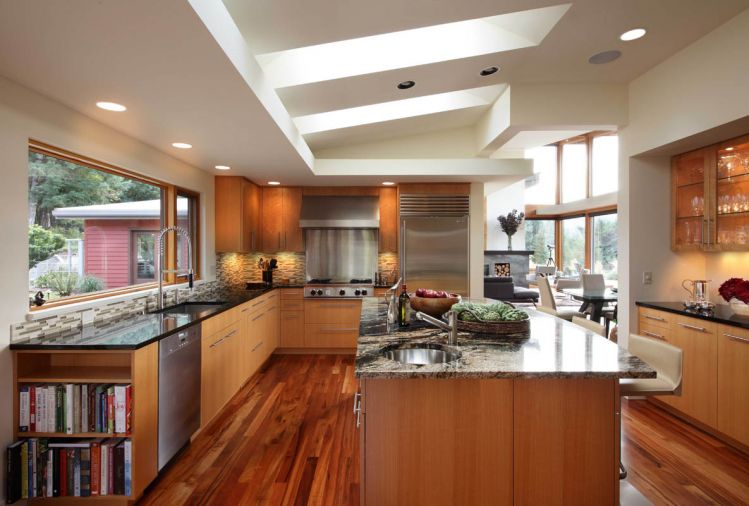 The kitchen is a large room, with plenty of space for guests to relax while the couple cooks. The rich finishes includes beautiful granite on the island, which Marilyn likens to the “galaxy” because of its stellar swirls and Tiger wood on the floor. The green and clear glass tiling in the black splash continues that one accent color from the living and dining rooms. The upper cabinets are finished in figured anigre veneer, while the bottom cabinets feature straight anigre veneer.