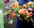 Eye-catching orange and chocolate tones highlight a bouquet of copper beech, black elderberry, ranunculus, sweet peas, grasses, mallow, nine bark, bronze fennel and snowberry foliage.