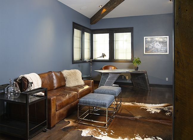 In the downstairs study, a space-age styled desk, leather couch, Parson-style ottomans and hide rugs are united in the home’s modern rustic theme.