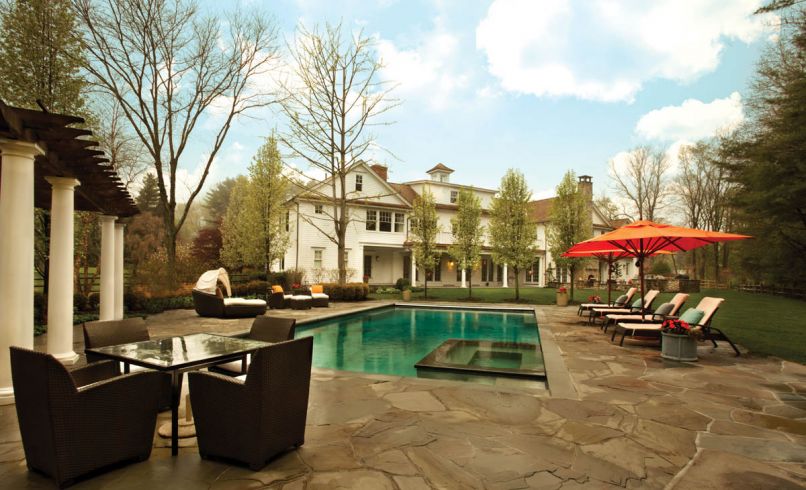 A pool house provides shower/bathroom and kitchenette for a full day of play at the pool. The master bedroom's newly added porch provides a covered patio below. Umbrellas give pops of color around the pool.