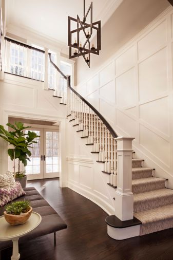 Boxed panels line the entry walls, where horizontal artwork is softened by a fiddle leaf plant. A Bernhardt bench shines beneath the Lillian August lantern.