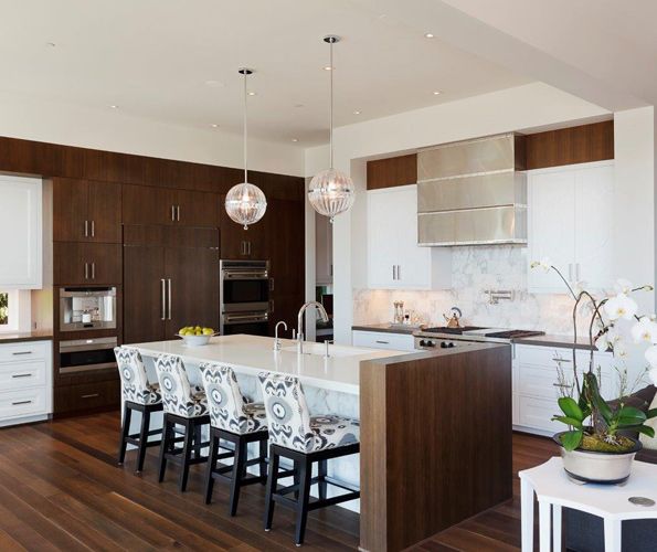 One crucial element in the design palette was the Calcutta gold 12” x 24” tile cut down to 6” x 24” stacked tiles that form the kitchen backsplash. A custom stainless hood with chrome banding and rivets adds a unique, modern touch. Traditional square-edged antique nickel hardware reigns in the modern feel. Bar stools by Jessica Charles with fabric by COM from Bedford Brown. To create contrast, pure white cabinets are set against eight shades of white found throughout house.