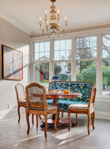 The back wall of the previous kitchen had held cabinets and a lone window. To bring in more light and to accommodate a breakfast area, the cabinetry was removed, the wall was pushed out and a bank of tall windows was added. A Murano glass chandelier – which the homeowners purchased in Venice – now hangs in the new space.