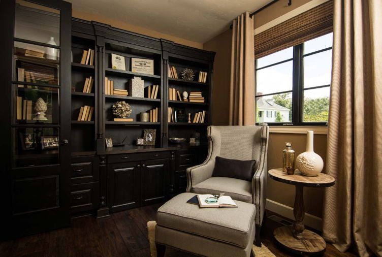 In the den, espresso-stained cabinets and shelves designed by O’Brien hold books, mementos and family photographs near an inviting wing chair and ottoman in the den, which O’Brien also designed.