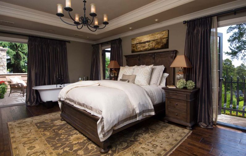 French doors open to a deck and balcony and ensure plenty of light reaches the master bedroom. The bathtub is positioned to take advantage of views outside or of the fireplace. A bed from Restoration Hardware dressed in Pottery Barn linens sits beneath a coffered ceiling that gives the room added dimension and drama.