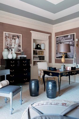 Maison Charles gilded and bronze pineapple lamp with worn doré bronze-patinated shade stands on an 18th century bureauplot. The back wall of this bachelor bedroom is upholstered in gray flannel outlined in nailheads, which is hung with Piranesi prints framed in white gold frames.