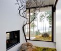 Budget-friendly, green building solutions include a double-sided steel manufactured fireplace found on Craigslist and framed in black-painted glass that reflects the outdoors. Live moss, rock and a dried Madrona branch greet guests, maintaining visual flow of natural vegetation from outdoors in.