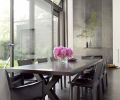 A long dining table runs parallel to the new 10-foot by 10-foot sliding glass door set beneath the jalousie window. The fireplace in the background was given a new surround and mantel of hot rolled steel.